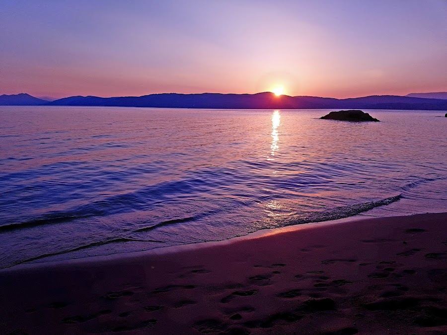 Calm clear water and gold sand inside the small cove of Little Banana on Skiathos