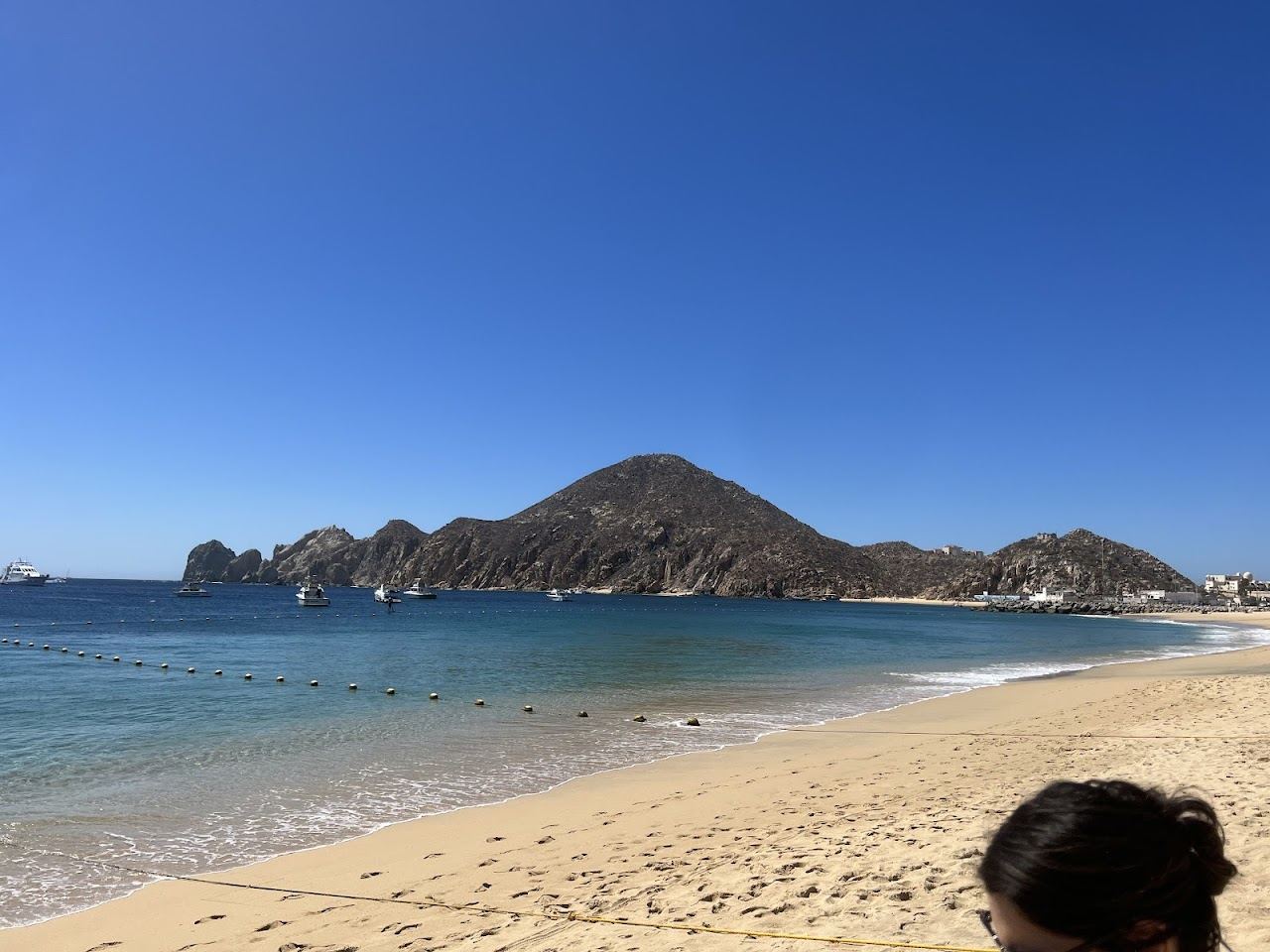 Golden sand, beach umbrellas and clear water at Medano Beach in Cabo San Lucas