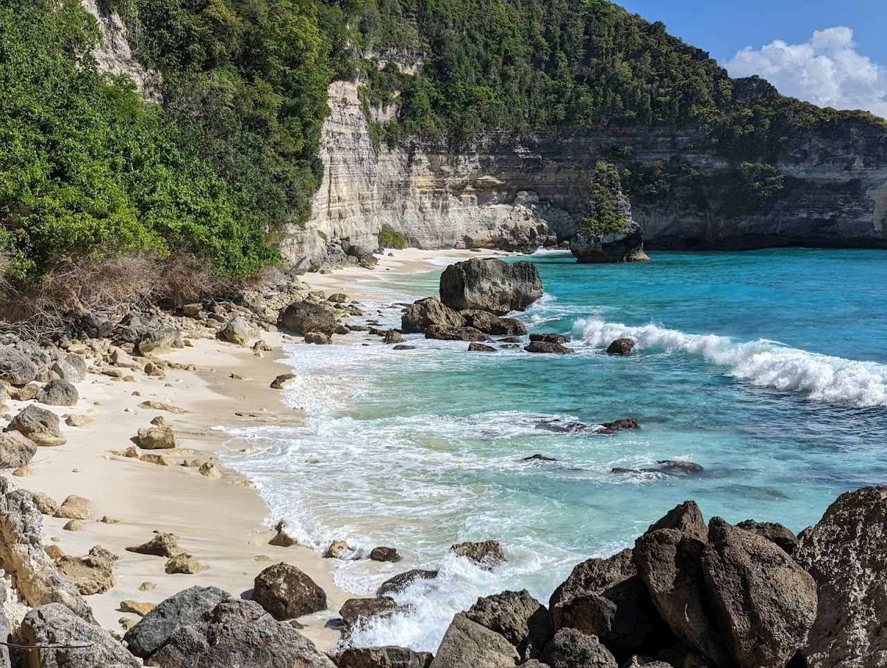 The remote white sand cove of Suwehan Beach below tall cliffs on the south east coast of Nusa Penida